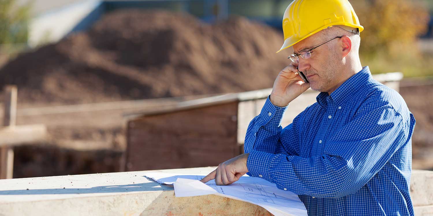 Pinal County worker looking at blueprints and talking on a cell phone