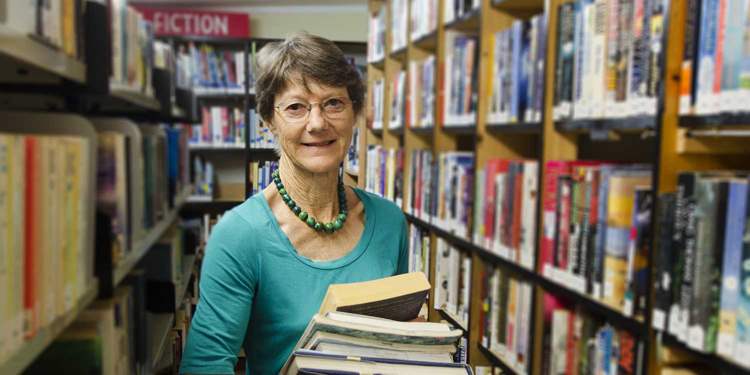Pinal County librarian carrying books in a library